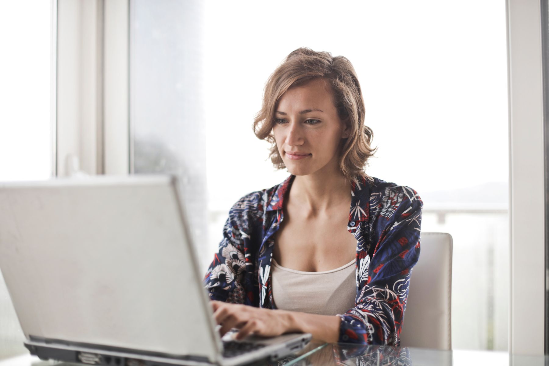 Een vrouw werkt op haar laptop in een lichte werkkamer.