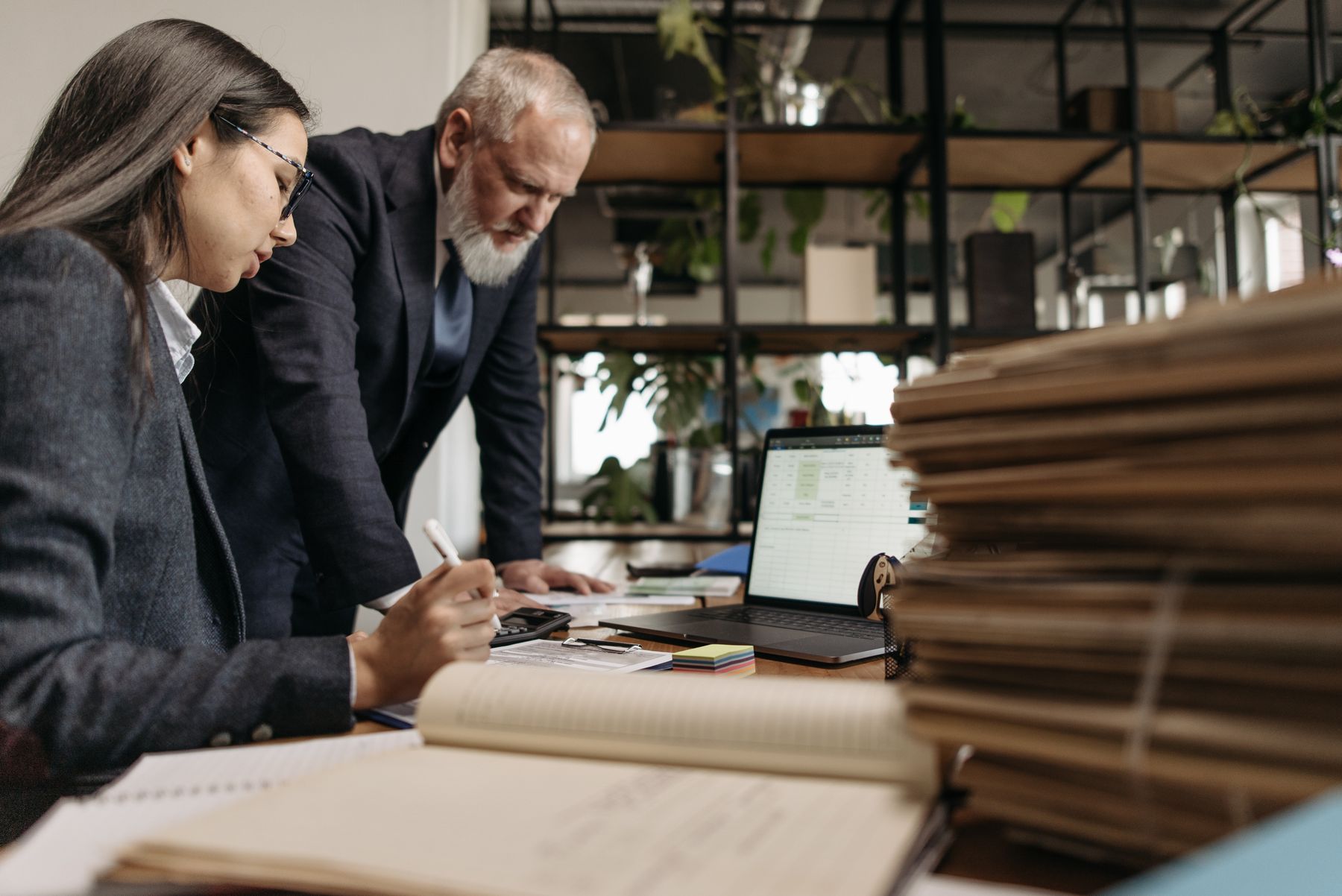 Twee collega’s bekijken samen iets op een laptop aan een bureau.
