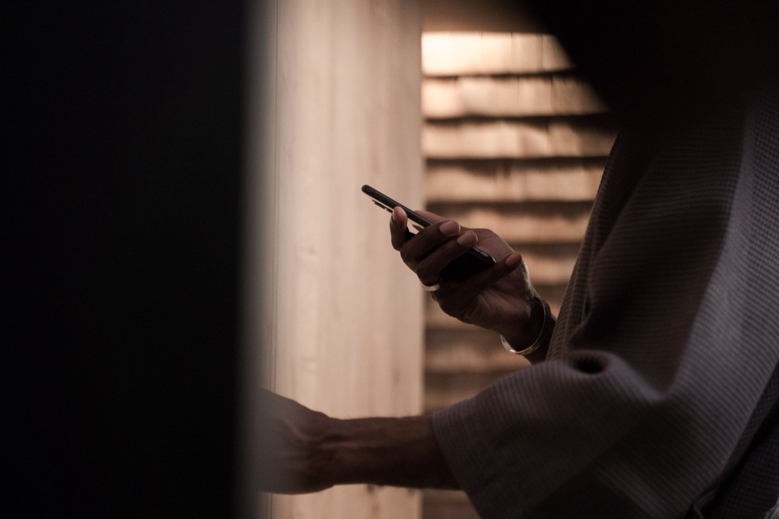 Iemand leest een bericht op een telefoon, in warm avondlicht.